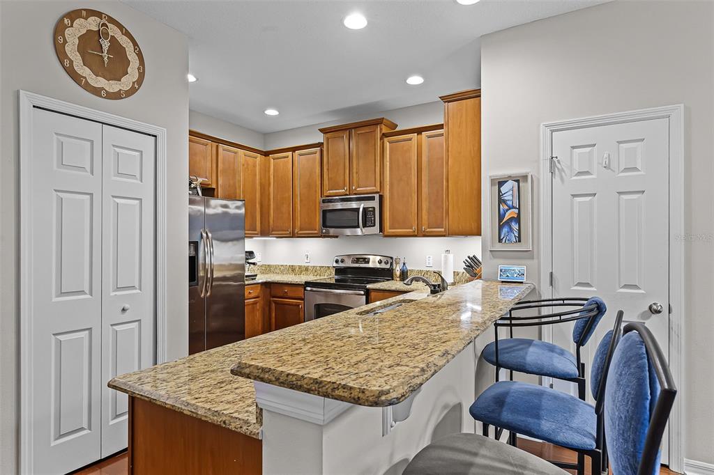 14242 Desert Haven Street, Unit GE Windermere, FL 34786 - Photo 8 of 32 a kitchen with kitchen island granite countertop wooden cabinets a stove a sink a oven with a dining table and chairs