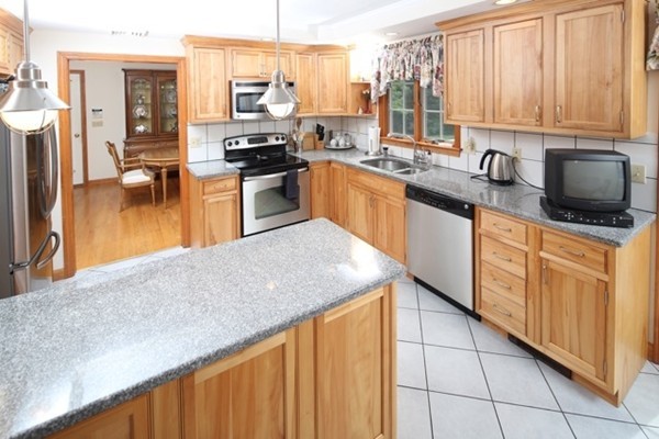 22 Ilex Road Marshfield, MA 02050 - Photo 6 of 21 a kitchen with stainless steel appliances granite countertop a stove a sink dishwasher and a microwave oven with wooden cabinets