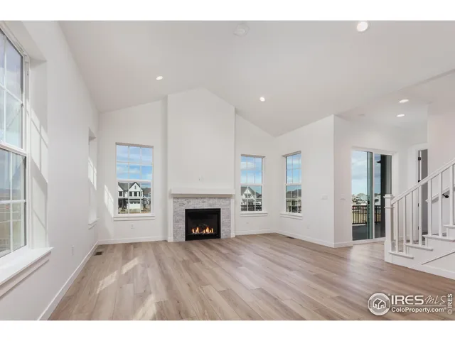 a view of an empty room with wooden floor fireplace and a window