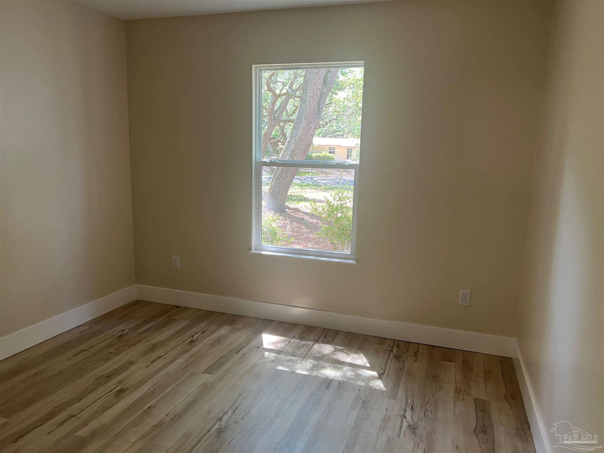 3111 Holley Point Road Navarre, FL 32566 - Photo 17 of 23 a view of an empty room with wooden floor and a window