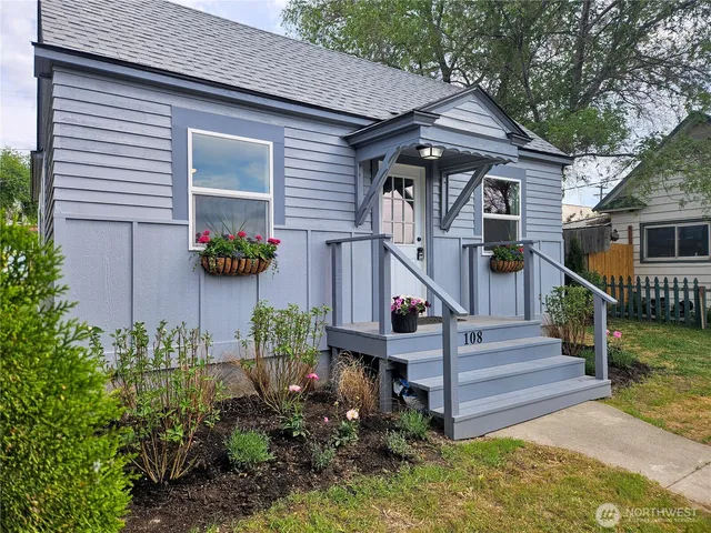 a front view of a house with wooden fence and a bench