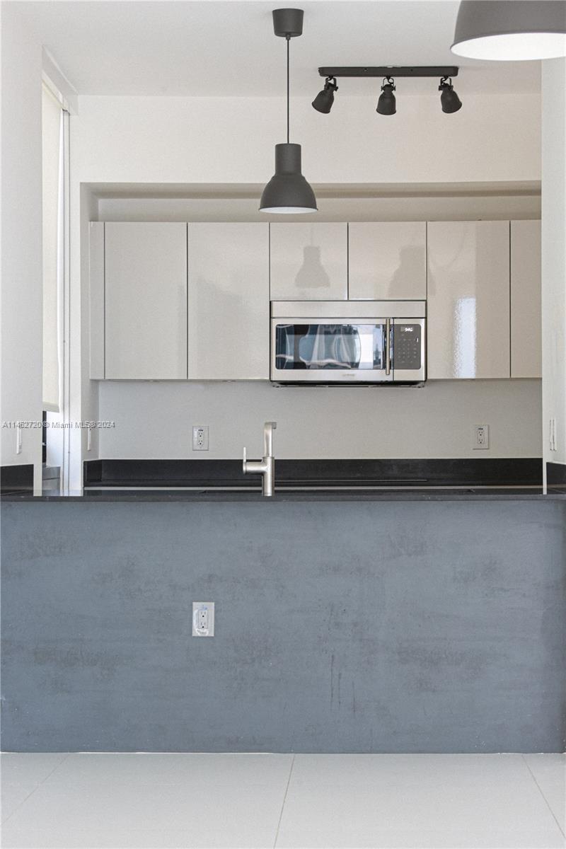 1010 Brickell Avenue, Unit 2505 Miami, FL 33131 - Photo 54 of 61 a kitchen with stainless steel appliances granite countertop a sink a stove and white cabinets