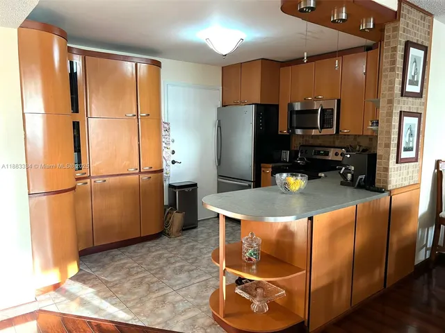 a kitchen with stainless steel appliances granite countertop a refrigerator a stove and a sink with granite countertops