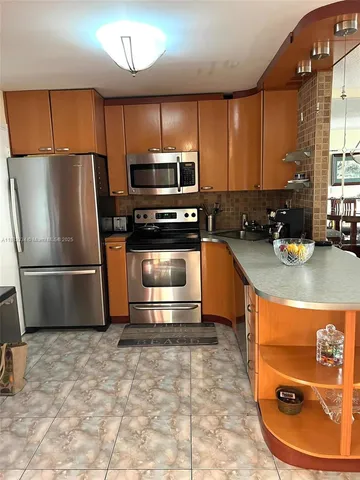 a kitchen with stainless steel appliances granite countertop a sink a stove a microwave and a refrigerator