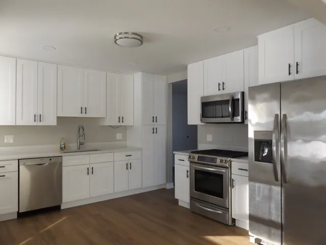 a kitchen with cabinets stainless steel appliances and wooden floor