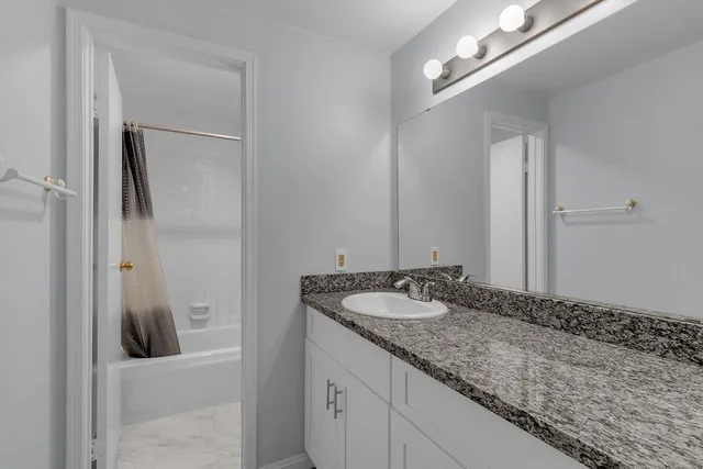 a en suite bathroom with a granite countertop sink and a mirror