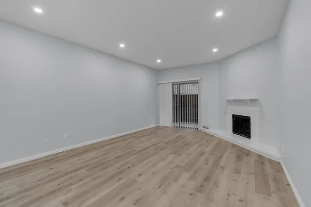 a view of empty room with wooden floor and fireplace