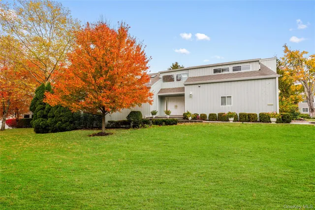 a view of a white house with a big yard and large trees