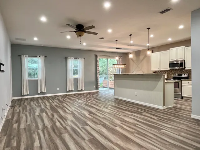 an open kitchen with kitchen island a sink dishwasher stove and oven with wooden floor