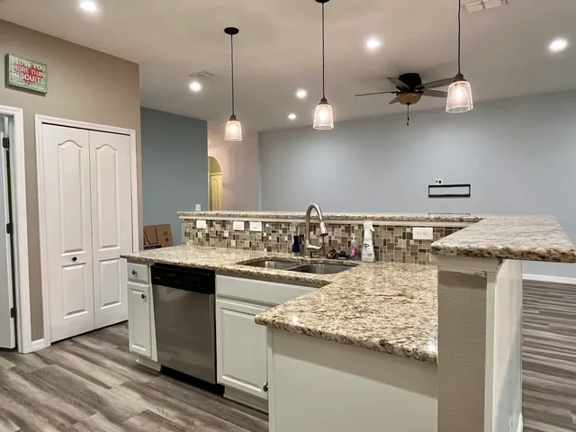a kitchen with a sink a counter space appliances and cabinets