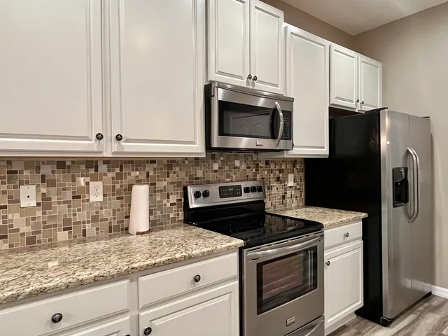 a kitchen with granite countertop white cabinets and stainless steel appliances