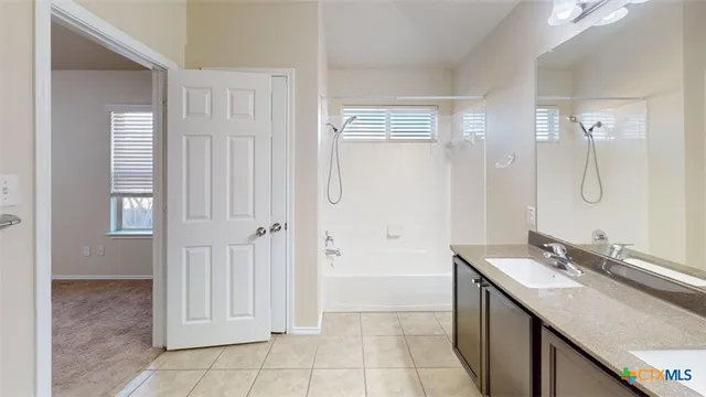 a bathroom with a granite countertop bathtub shower sink vanity and toilet