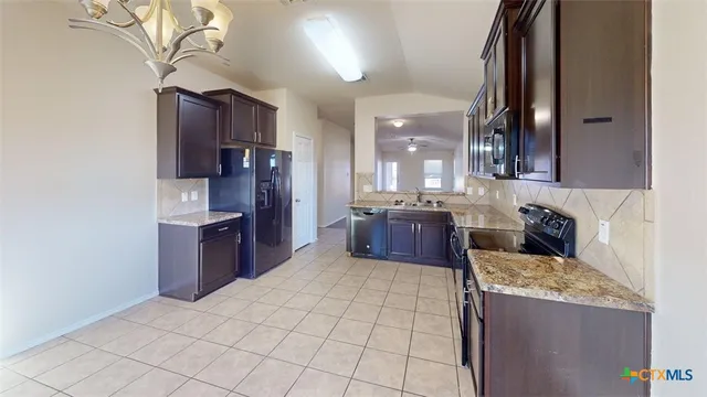 a kitchen with stainless steel appliances granite countertop a refrigerator a stove and a sink with wooden cabinets