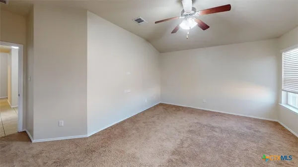 an empty room with chandelier fan and windows