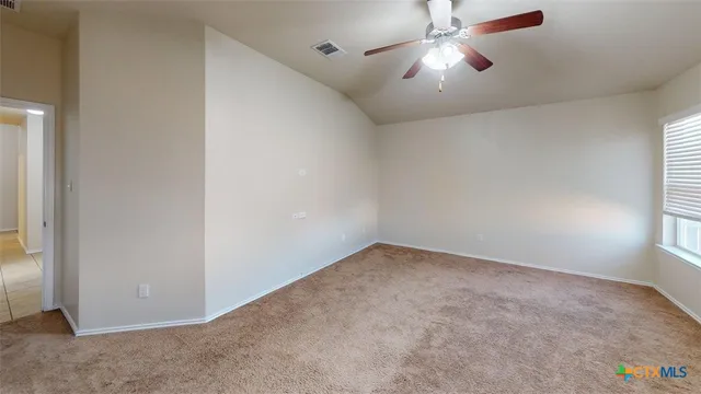 an empty room with chandelier fan and windows