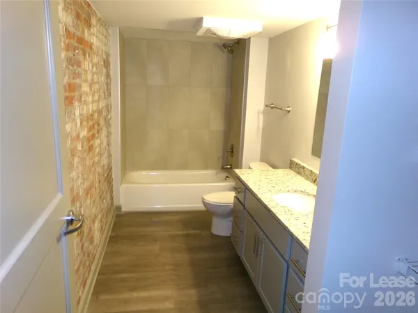 an empty room with wooden floor and windows with curtains