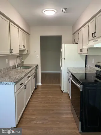 a kitchen with stainless steel appliances granite countertop a sink and cabinets with wooden floor