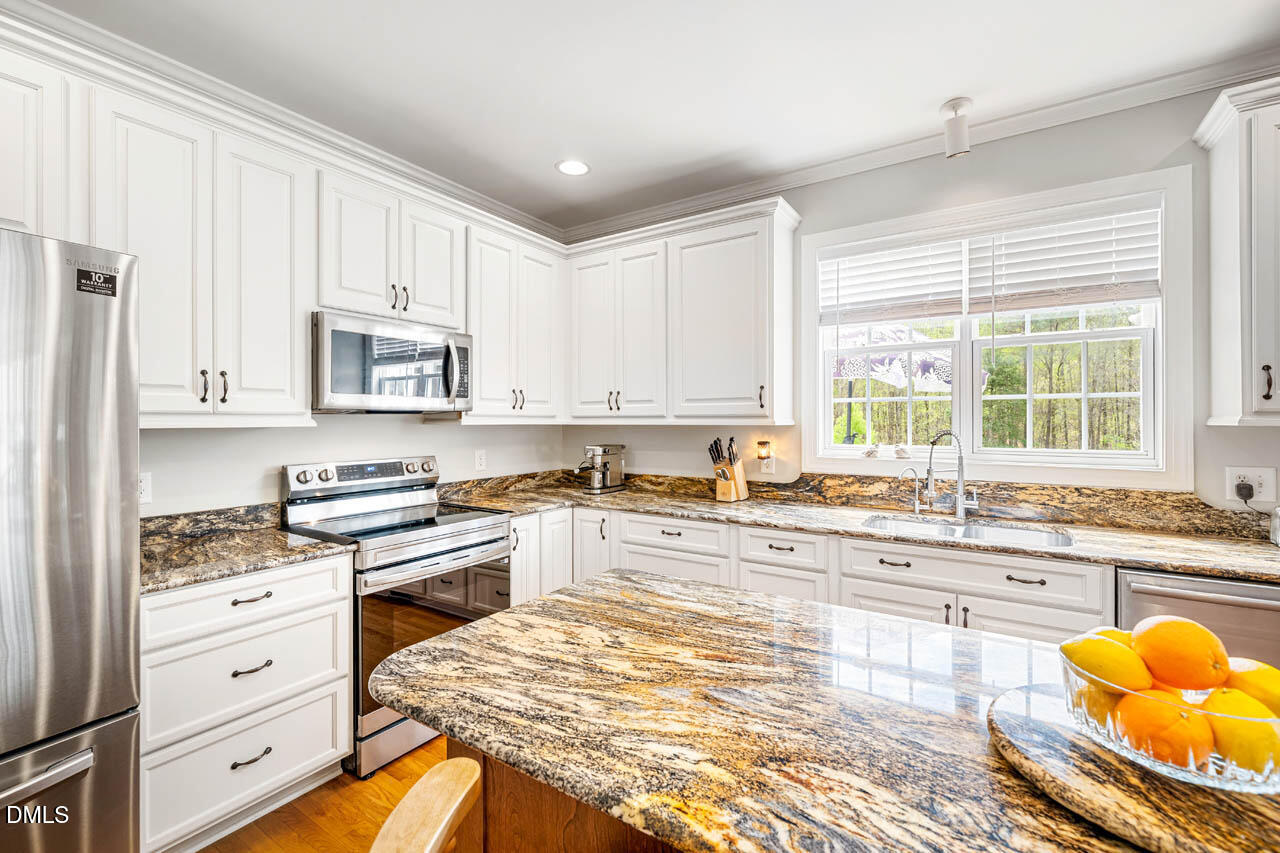 265 Old Chestnut Crossing Moncure, NC 27559 - Photo 15 of 45 a kitchen with stainless steel appliances granite countertop a stove a sink and white cabinets with wooden floor