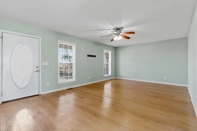 an empty room with windows and fan
