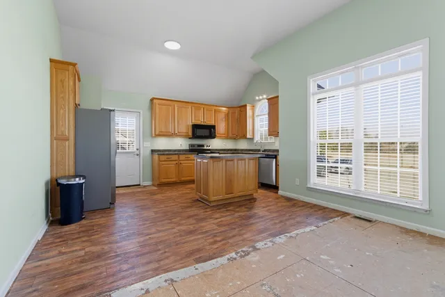 a view of kitchen with stainless steel appliances granite countertop a stove top oven a refrigerator a sink and dishwasher with wooden floor
