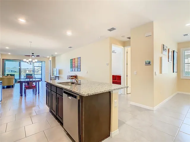 a kitchen with stainless steel appliances granite countertop a stove top oven a sink dishwasher and a refrigerator with wooden cabinets