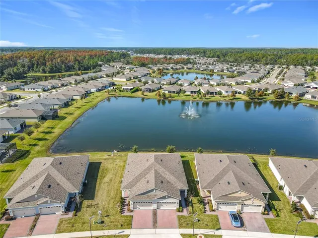 an aerial view of a tennis ground and a cars park side of the road
