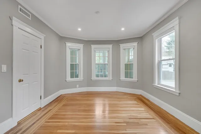 a view of empty room with wooden floor and fan