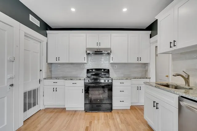 a kitchen with stainless steel appliances granite countertop a stove and white cabinets
