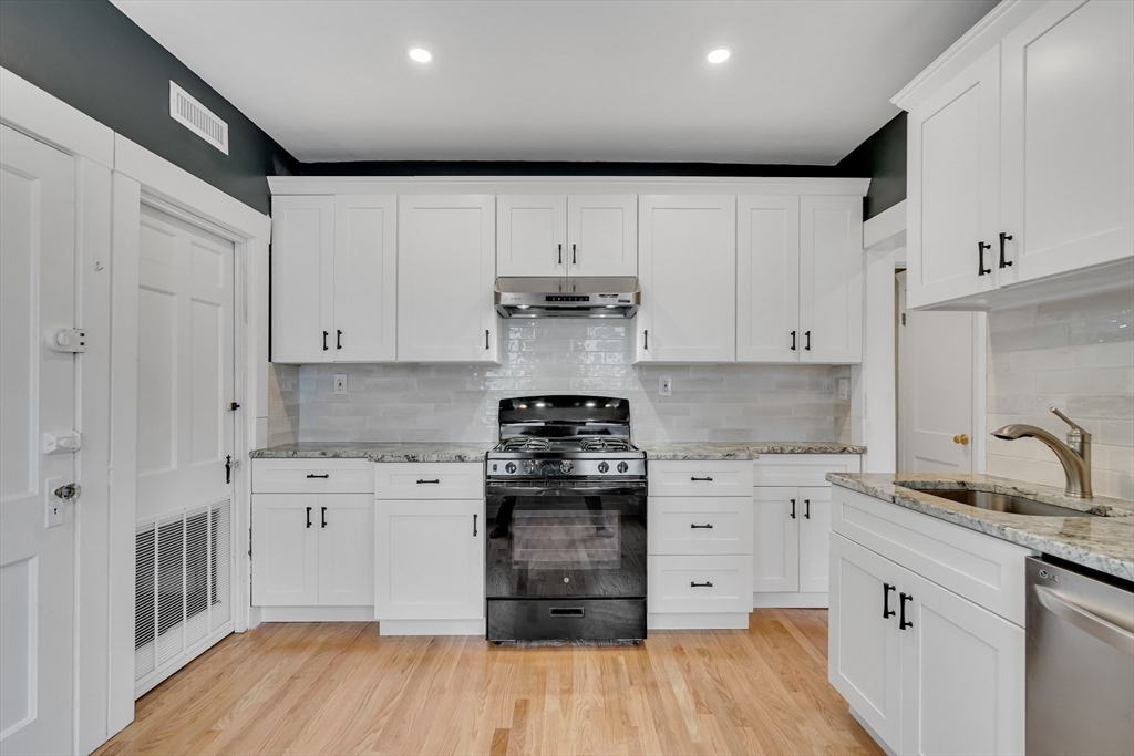 701 Hammond Street, Unit 1 Brookline, MA 02467 - Photo 9 of 28 a kitchen with stainless steel appliances granite countertop a stove and white cabinets