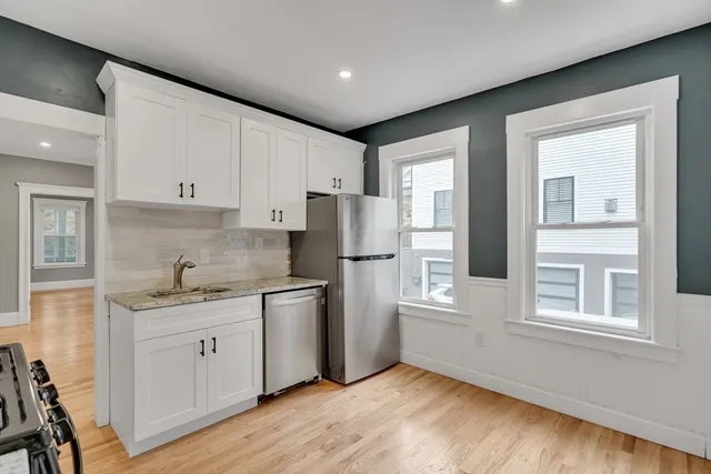 a kitchen with stainless steel appliances granite countertop a refrigerator sink and white cabinets
