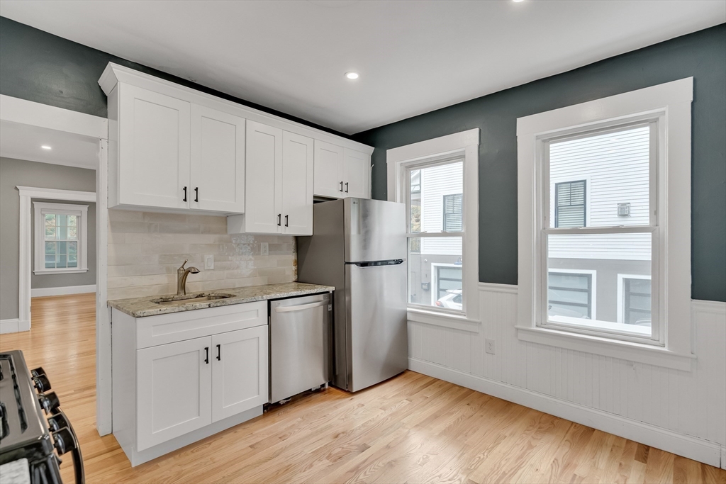 701 Hammond Street, Unit 1 Brookline, MA 02467 - Photo 10 of 28 a kitchen with stainless steel appliances granite countertop a refrigerator sink and white cabinets
