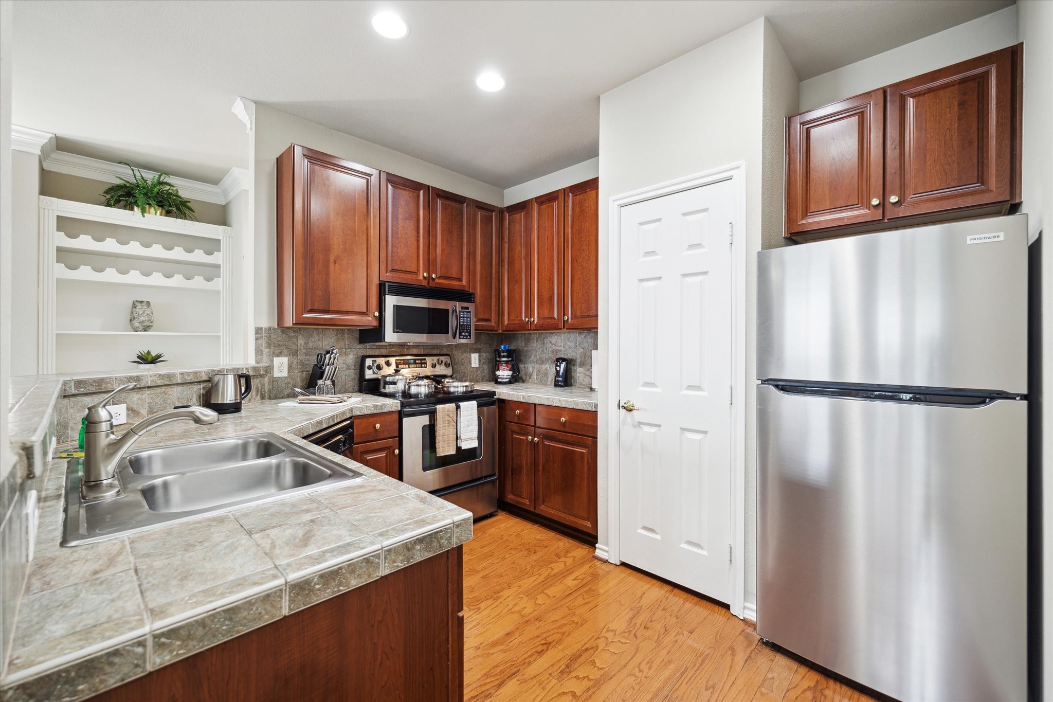 2400 McCue Road, Unit 460 Houston, TX 77056 - Photo 7 of 21 a kitchen with a refrigerator a stove a sink dishwasher and wooden cabinets with wooden floor