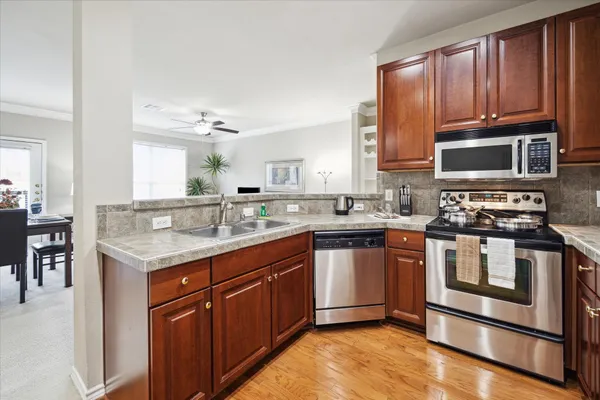 a kitchen with stainless steel appliances granite countertop a stove a sink dishwasher and a microwave oven with wooden floor