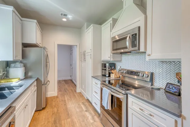 a kitchen with stainless steel appliances granite countertop a refrigerator a stove top oven a sink and dishwasher