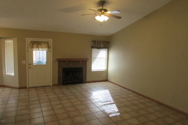 a view of an empty room with window and chandelier fan