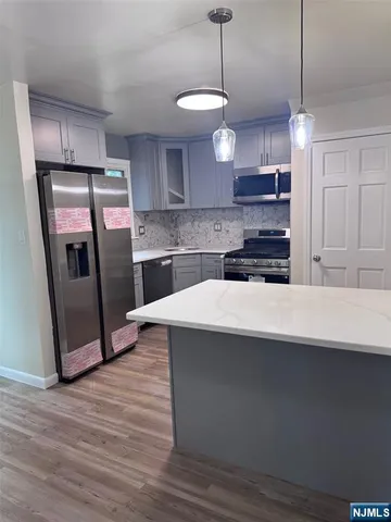 a kitchen with stainless steel appliances a sink a refrigerator a center island a stove and cabinets