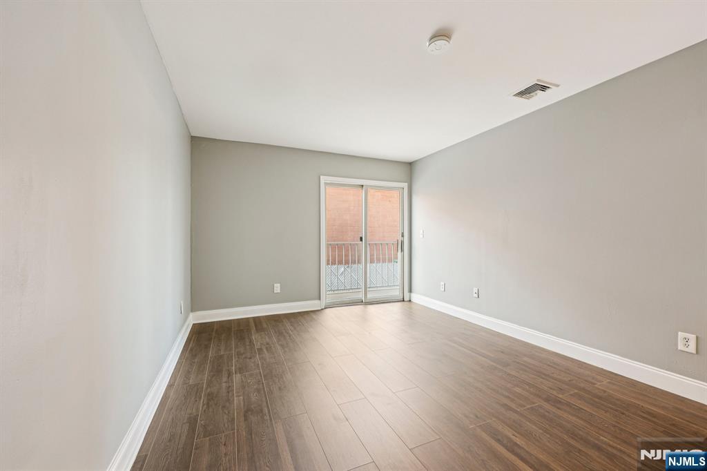 105 State Street, Unit 1H Hackensack, NJ 07601 - Photo 20 of 23 a view of an empty room with wooden floor and windows