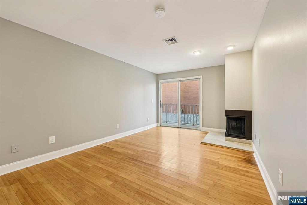 105 State Street, Unit 1H Hackensack, NJ 07601 - Photo 6 of 23 a view of an empty room with wooden floor and a window