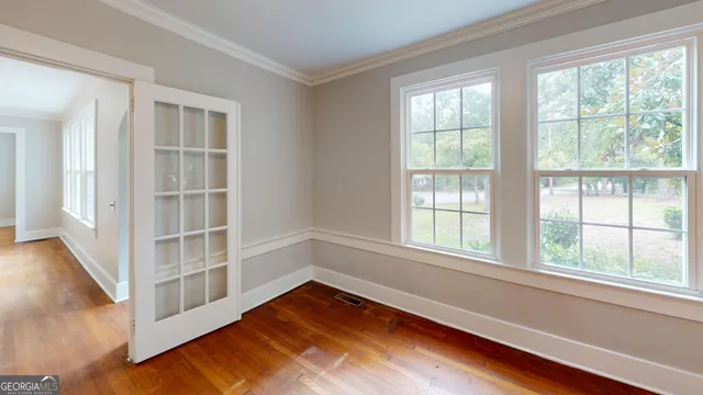 an empty room with wooden floor and windows
