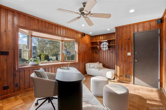 a living room with furniture a ceiling fan and a large window
