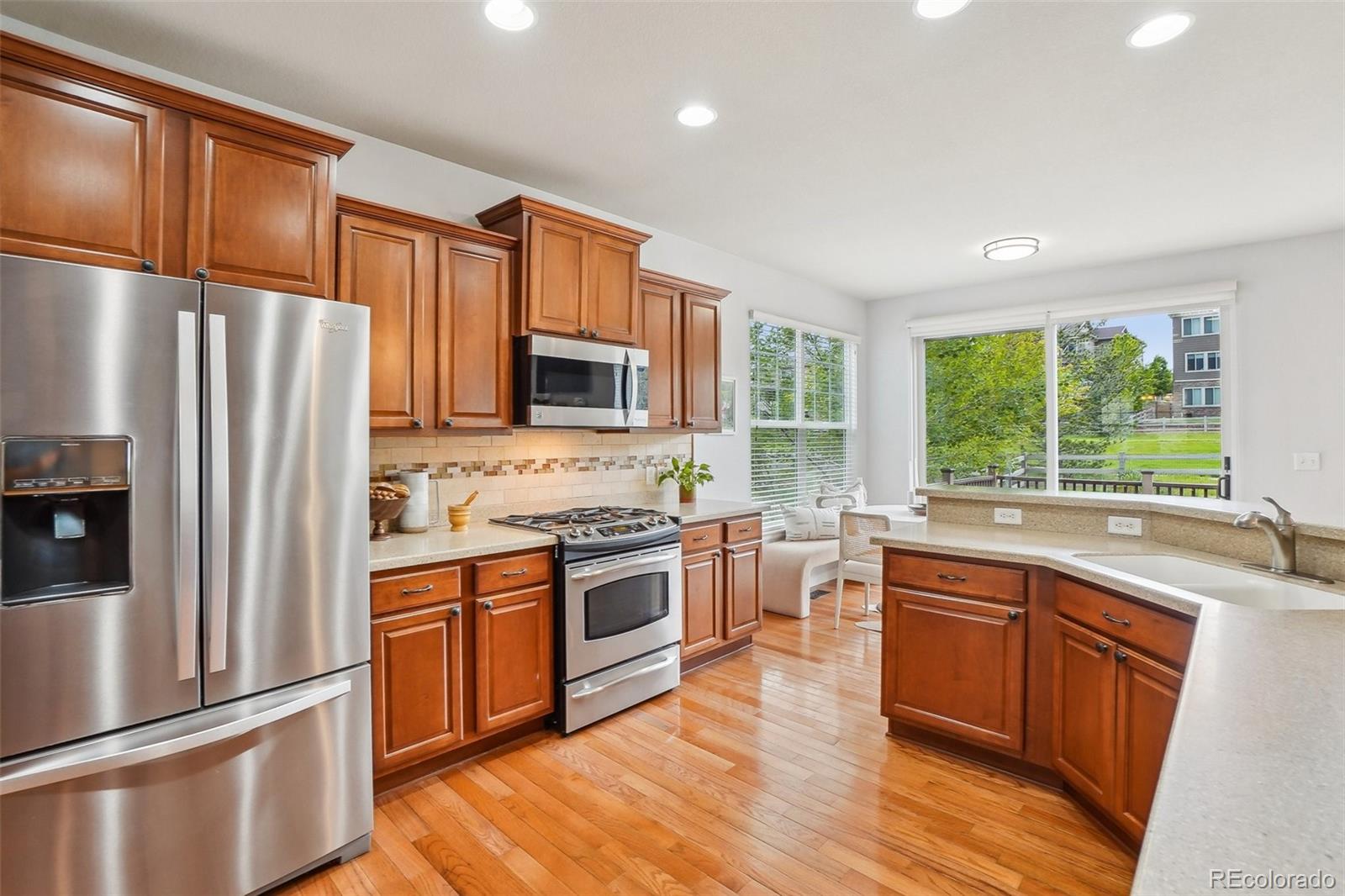 2605 Gray Wolf Loop Broomfield, CO 80023 - Photo 13 of 49 a kitchen with stainless steel appliances granite countertop a refrigerator a sink dishwasher a stove top oven a refrigerator with white cabinets and wooden floor