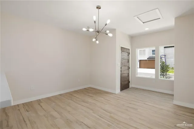 an empty room with wooden floor chandelier fan and windows