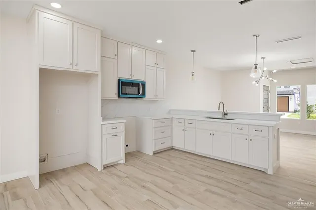 a large kitchen with cabinets stainless steel appliances a sink and wooden floor