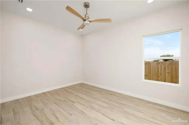 an empty room with a window and ceiling fan