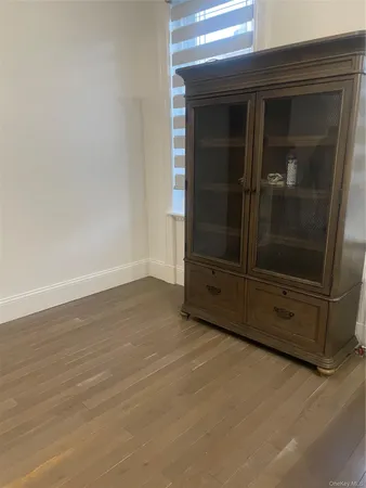 an empty room with wooden floor and cabinet