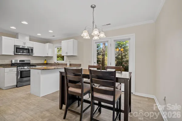 a kitchen with stainless steel appliances granite countertop a dining table chairs stove and refrigerator
