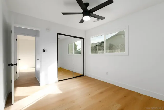 a view of a livingroom with a chandelier fan and wooden floor