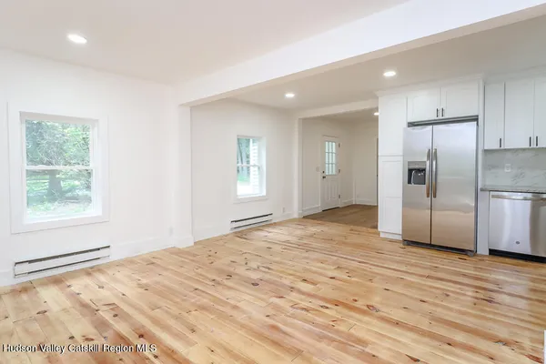 a view of a kitchen with wooden floor electronic appliances and windows