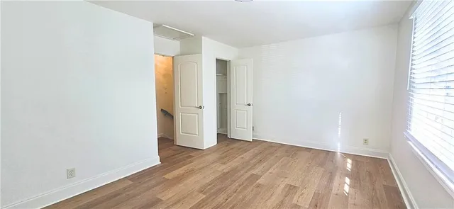 an empty room with wooden floor and windows