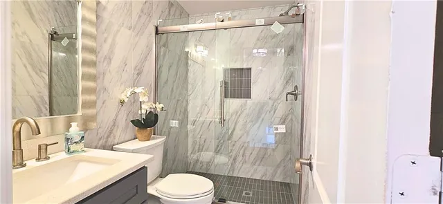 a bathroom with a sink vanity granite toilet and shower
